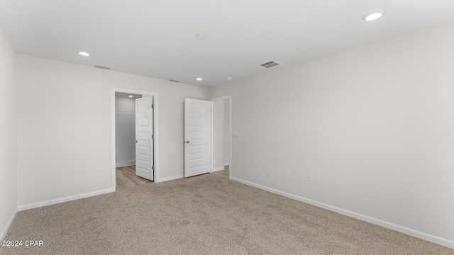 unfurnished bedroom with light colored carpet and a closet