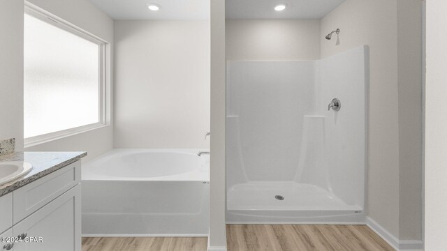 bathroom with plus walk in shower, vanity, and hardwood / wood-style flooring