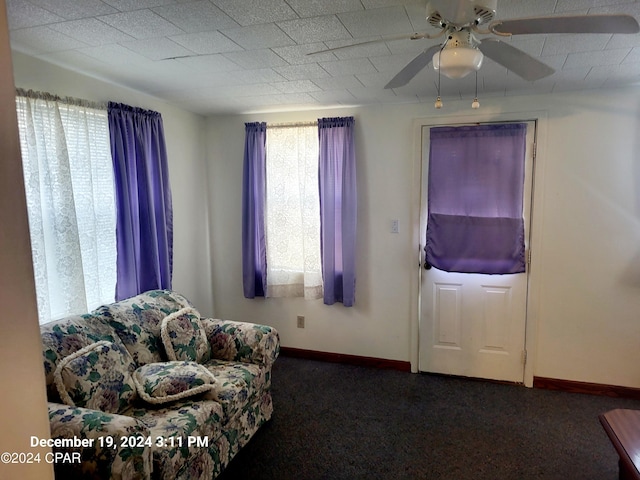 sitting room with dark carpet, plenty of natural light, and ceiling fan