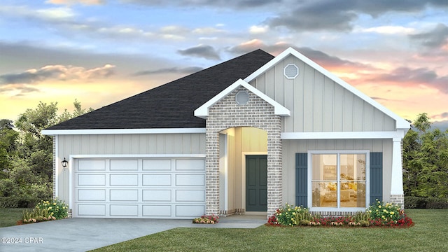 view of front of house with a lawn, driveway, an attached garage, a shingled roof, and brick siding