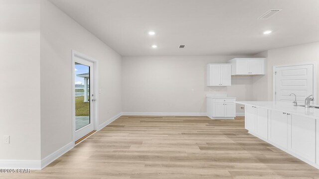 kitchen with dishwasher, white cabinetry, sink, a kitchen island with sink, and a raised ceiling