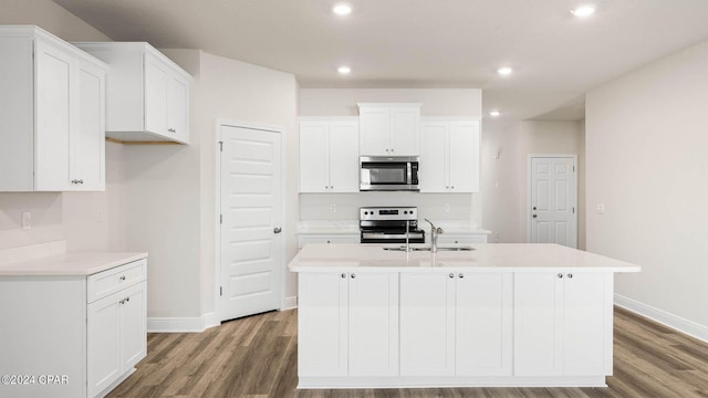 kitchen with sink, appliances with stainless steel finishes, a kitchen island with sink, hardwood / wood-style floors, and white cabinets