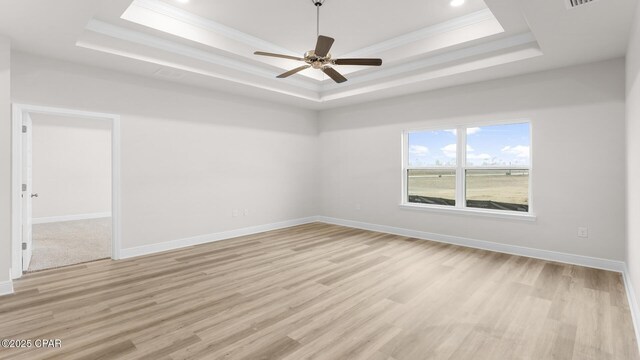 spare room with ceiling fan, a tray ceiling, and light hardwood / wood-style floors