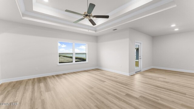 unfurnished living room with crown molding, ceiling fan, a tray ceiling, and light wood-type flooring