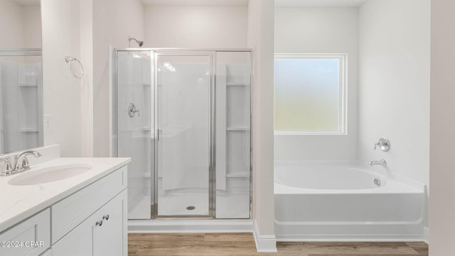 bathroom with plus walk in shower, hardwood / wood-style floors, and vanity