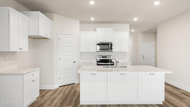 kitchen with stainless steel appliances, a kitchen island with sink, dark wood-type flooring, sink, and white cabinets