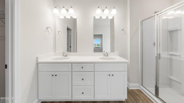 bathroom with wood-type flooring, vanity, and a shower with door