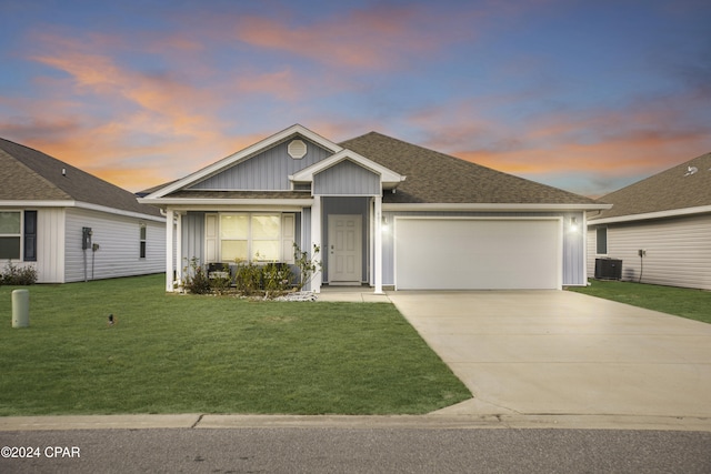 view of front of house featuring a lawn, a garage, and central air condition unit