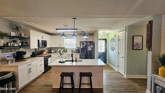 kitchen with sink, white cabinetry, a kitchen island with sink, and black appliances