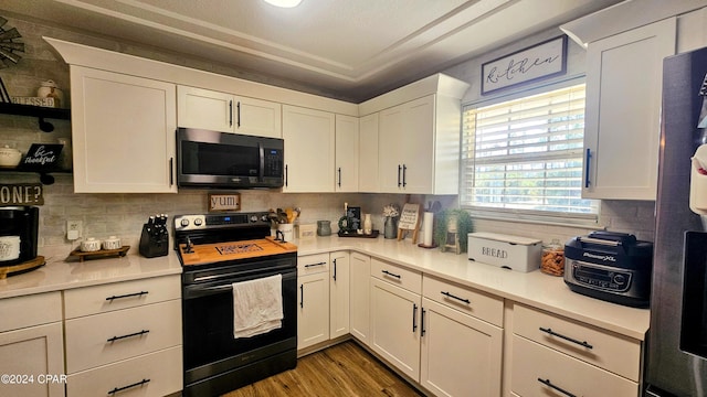 kitchen with white cabinets, decorative backsplash, wood-type flooring, and black range with electric cooktop