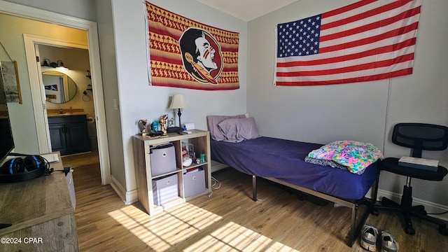 bedroom featuring wood-type flooring, ensuite bath, and sink