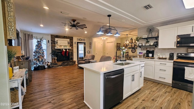 kitchen featuring a kitchen island with sink, white cabinets, hanging light fixtures, light wood-type flooring, and appliances with stainless steel finishes