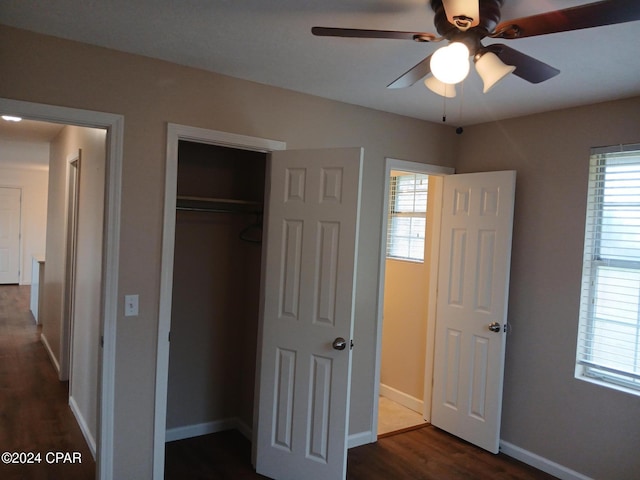 unfurnished bedroom featuring multiple windows, dark hardwood / wood-style flooring, a closet, and ceiling fan