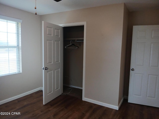 unfurnished bedroom featuring multiple windows, a closet, and dark hardwood / wood-style flooring