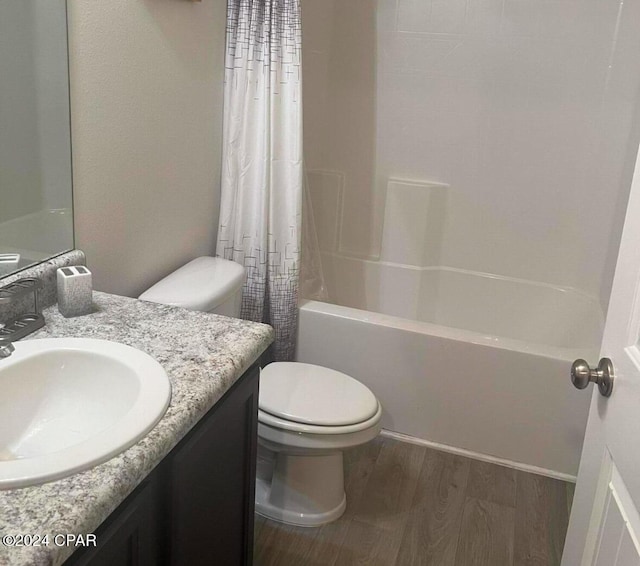 full bathroom with wood-type flooring, vanity, shower / tub combo, and toilet