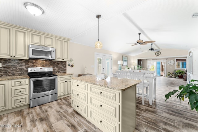 kitchen with pendant lighting, a center island, tasteful backsplash, cream cabinetry, and stainless steel appliances