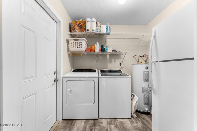 clothes washing area with independent washer and dryer, light wood-type flooring, a textured ceiling, and water heater