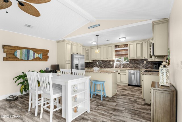 kitchen with pendant lighting, cream cabinets, a breakfast bar area, a kitchen island, and stainless steel appliances