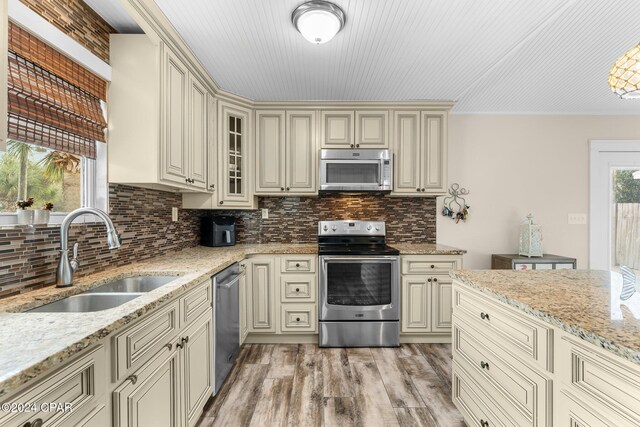 kitchen featuring light stone countertops, cream cabinets, stainless steel appliances, and sink