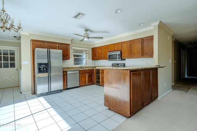 kitchen with kitchen peninsula, decorative light fixtures, appliances with stainless steel finishes, ceiling fan with notable chandelier, and ornamental molding