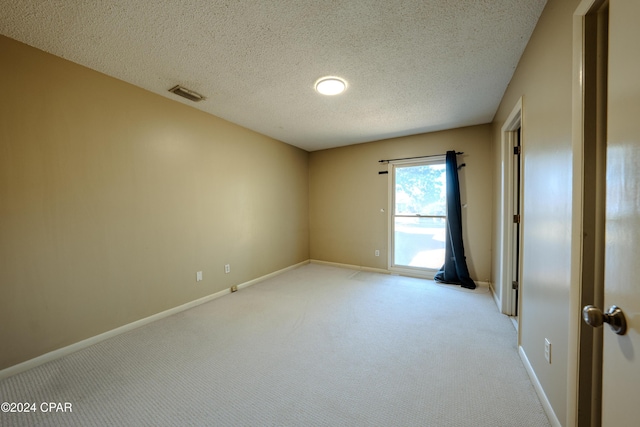 empty room with light colored carpet and a textured ceiling