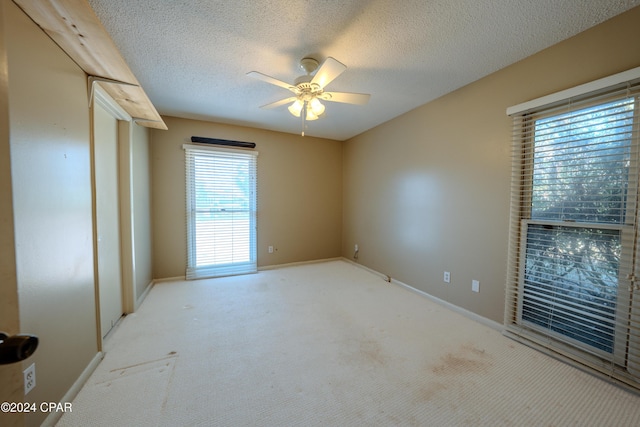 empty room with light carpet, a textured ceiling, and ceiling fan