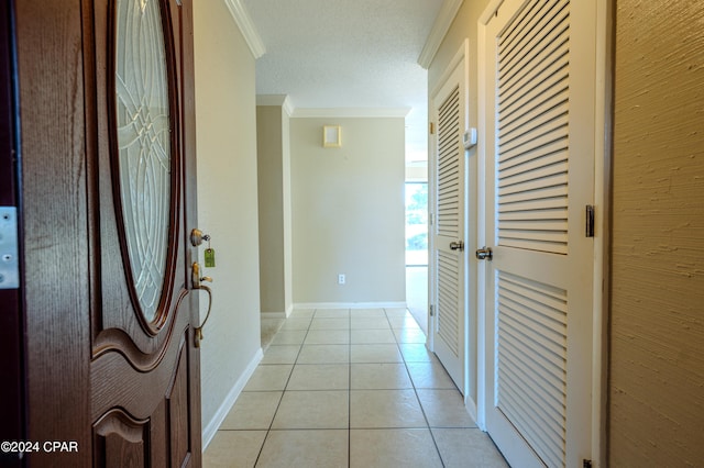 hallway with light tile patterned flooring, ornamental molding, and a textured ceiling