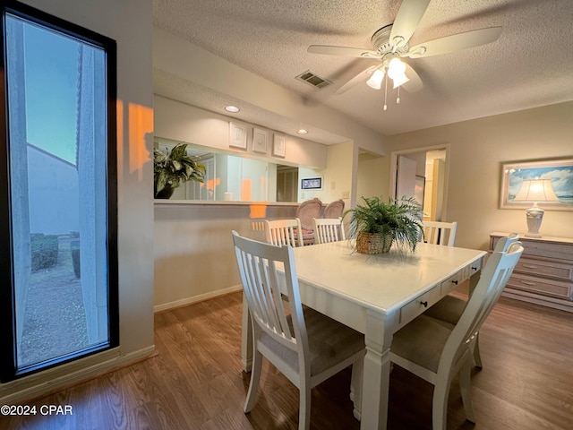 dining space with hardwood / wood-style floors, ceiling fan, and a textured ceiling