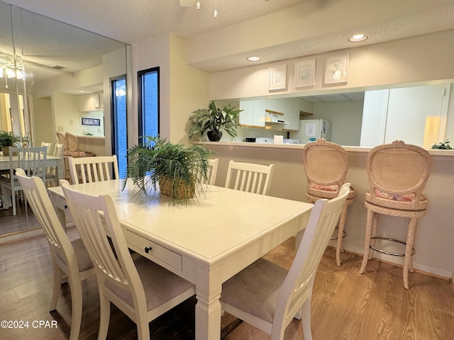 dining room featuring a textured ceiling, light hardwood / wood-style flooring, and ceiling fan