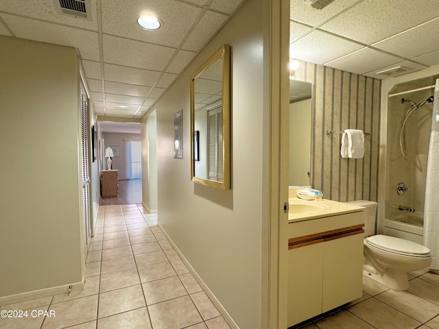 hallway with a drop ceiling and light tile patterned flooring