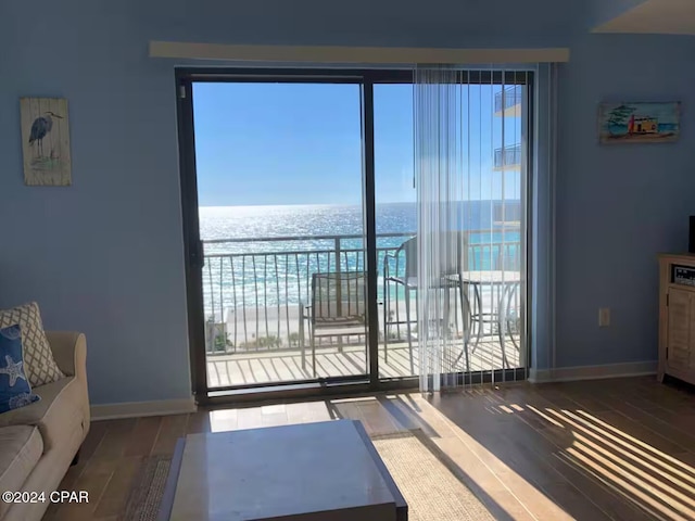 unfurnished living room with a beach view, a water view, and wood-type flooring