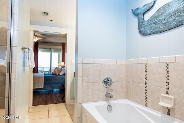 bathroom featuring tile patterned flooring, ceiling fan, and tiled tub