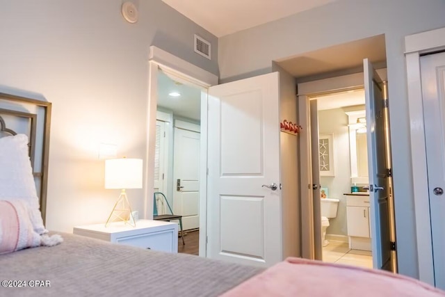 tiled bedroom featuring ensuite bathroom and a closet