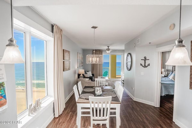 dining area with ceiling fan, a water view, and dark wood-type flooring