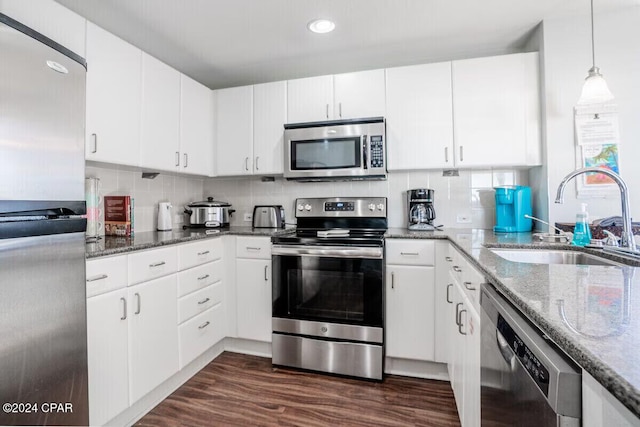 kitchen with sink, white cabinetry, stainless steel appliances, and dark stone counters