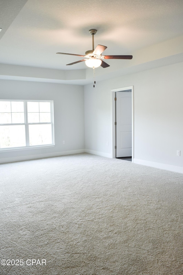 carpeted spare room featuring baseboards and ceiling fan