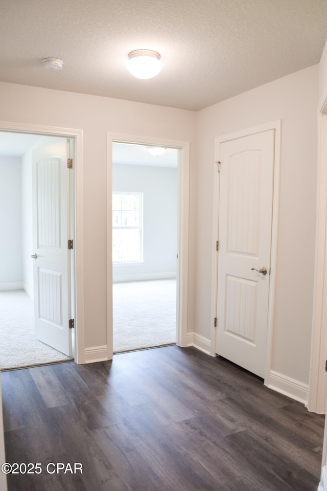 spare room featuring dark wood-style floors, baseboards, and a textured ceiling