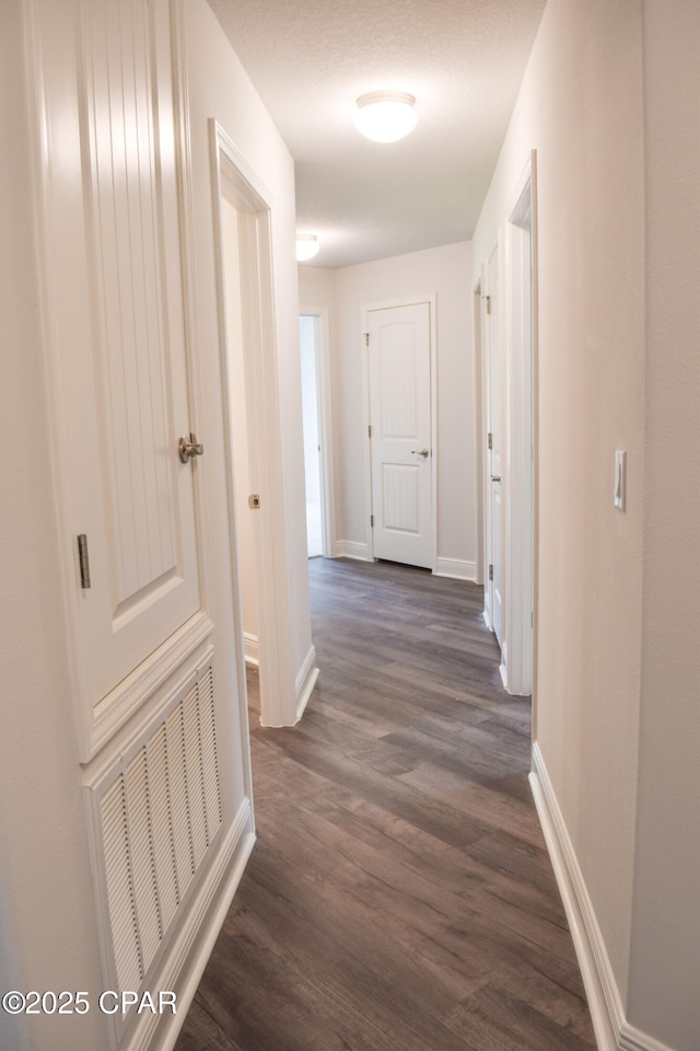 corridor with visible vents, dark wood-type flooring, and baseboards