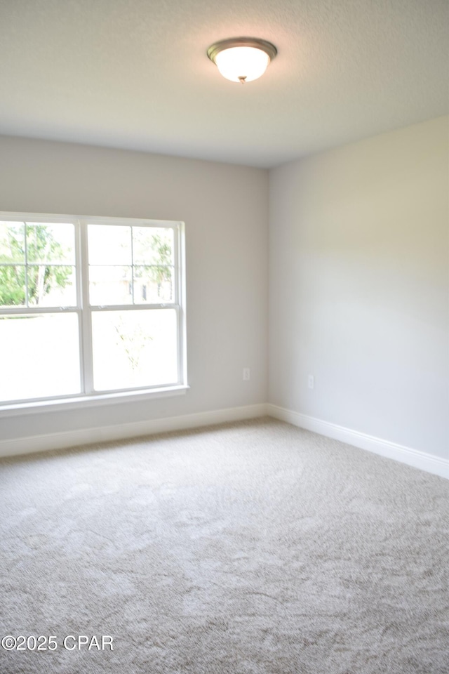 carpeted empty room featuring baseboards