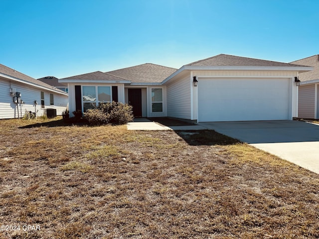 ranch-style home with central AC unit, a garage, and a front lawn