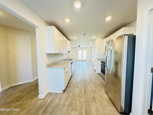 kitchen featuring white cabinets, light stone countertops, appliances with stainless steel finishes, and light hardwood / wood-style flooring