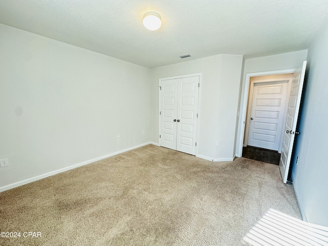 unfurnished bedroom with a textured ceiling, carpet floors, and a closet