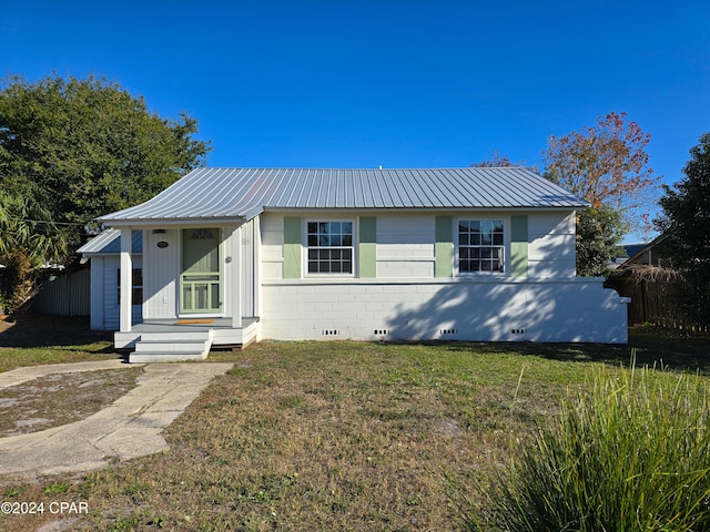 view of front of home featuring entry steps, concrete block siding, metal roof, crawl space, and a front lawn