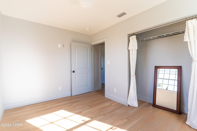 unfurnished bedroom with light wood finished floors, visible vents, and baseboards