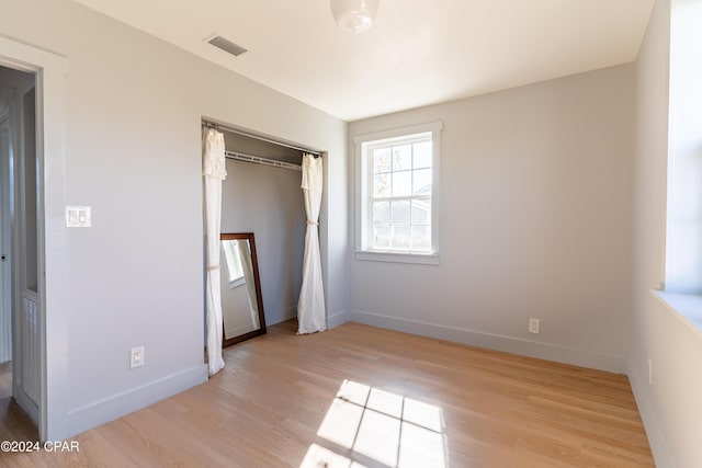 unfurnished bedroom with light wood-type flooring, a closet, visible vents, and baseboards