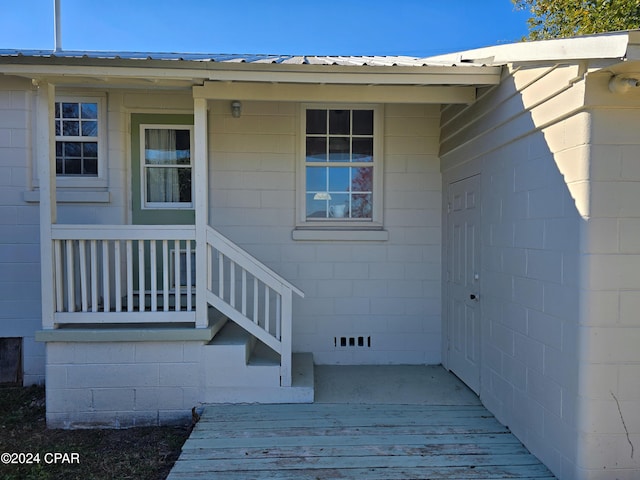 view of exterior entry featuring concrete block siding and metal roof