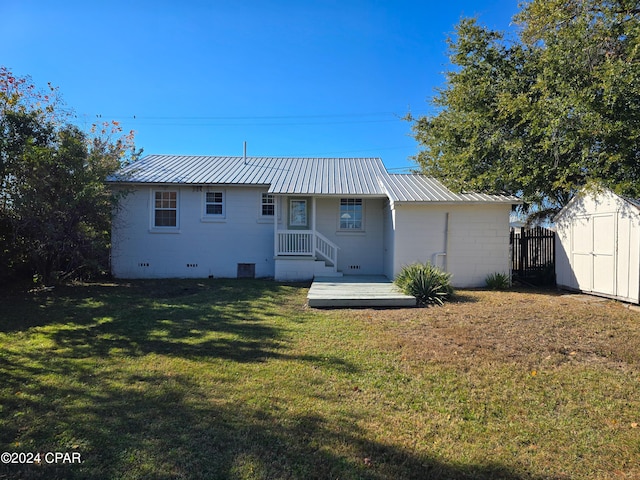 back of property featuring a lawn, metal roof, crawl space, an outdoor structure, and a shed