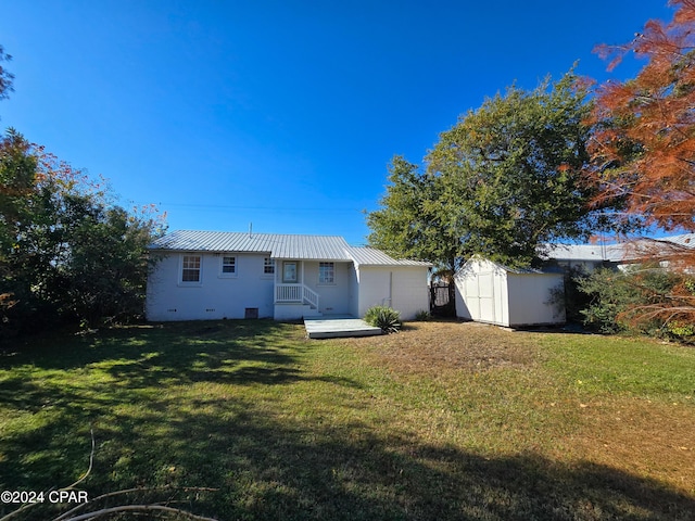 back of house with metal roof, a lawn, and a shed