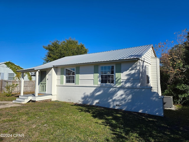 view of front of house featuring crawl space, central AC unit, metal roof, and a front yard