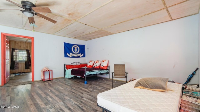 bedroom featuring dark hardwood / wood-style flooring, ceiling fan, and wooden walls